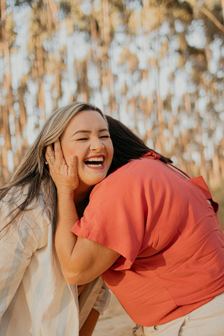 Two women embracing and laughing joyfully outdoors in São Paulo, Brazil.